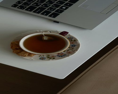 A laptop on a workspace table alongside a warm cup of herbal tea