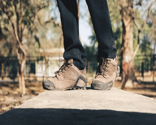 A pair of comfortable walking shoes near a park pathway with green grass